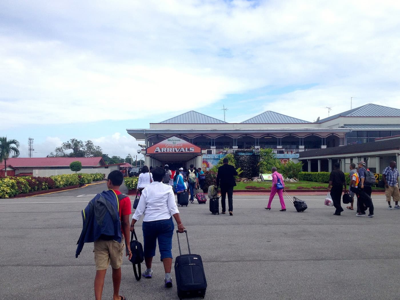 Passengers with luggage outside the arrivals building of Cheddi Jagan International Airport