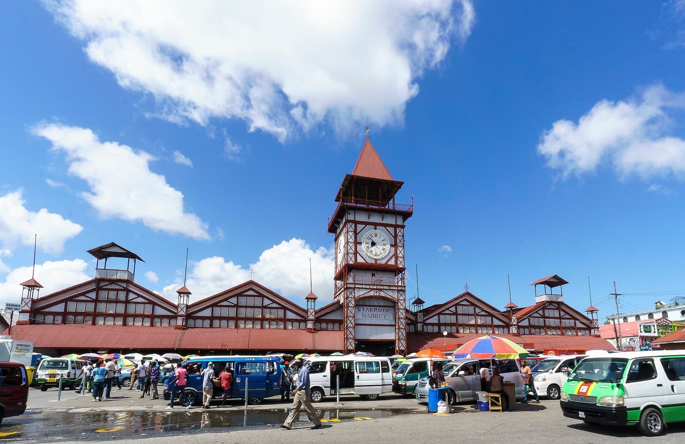 The red iron clock tower of Stabroek Market with minibuses parked in front