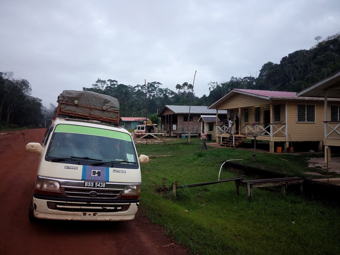 A loaded minibus parked beside wooden houses on the Linden–Lethem road