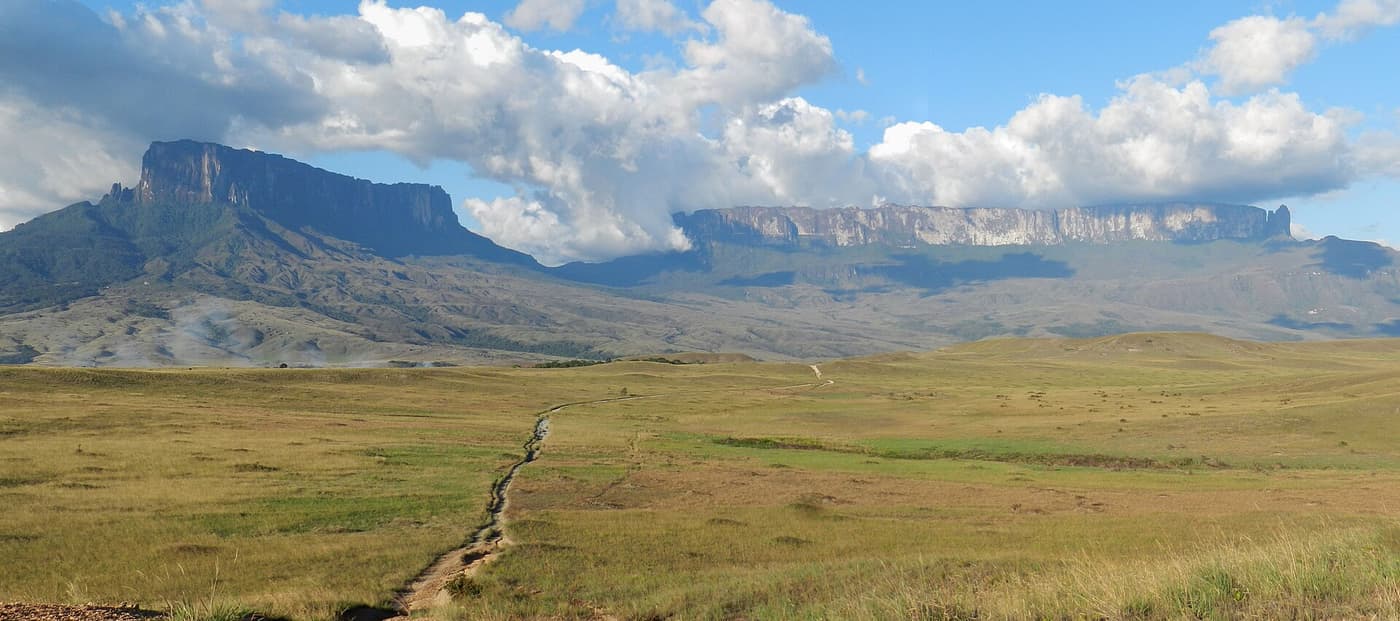 A footpath crossing open grassland towards the cliffs of Roraima and its neighbouring tepui