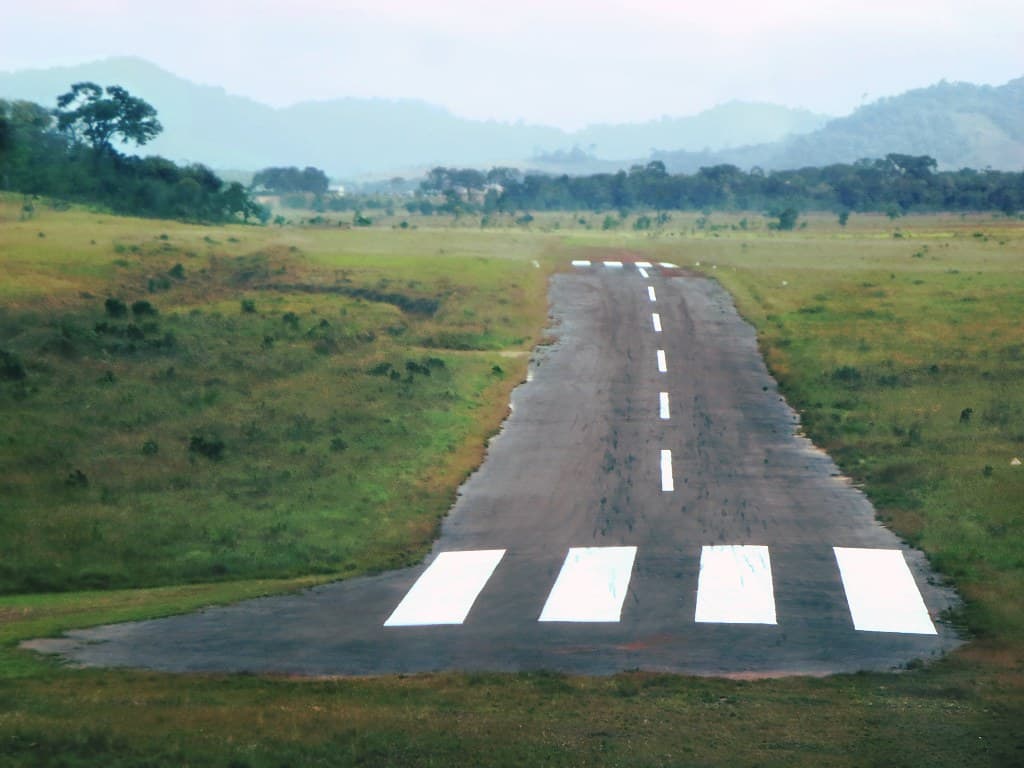The paved airstrip at Annai with grassland and misty hills beyond